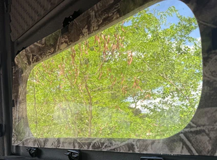 Magnetic camo curtain fitted over an open blind window, viewed from inside.